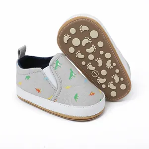 Detailweergave grijze babyloopschoenen met dinosauruspatroon en antislip rubberen zool