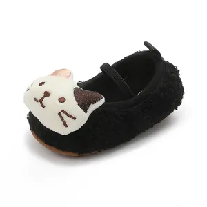 Detail of cute fuzzy baby shoes featuring a white cartoon cat face on black plush material.