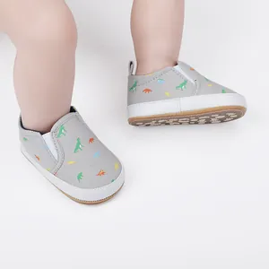 Detailweergave van grijze baby-instapschoenen met kleurrijke dinosaurusprints erop
