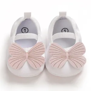 Close-up detail of soft sole white baby girl walking shoes with a pink butterfly ornament