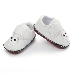 Nahaufnahme weißer Lauflernschuhe für Babys mit süßer Katzenapplikation und Handnähten