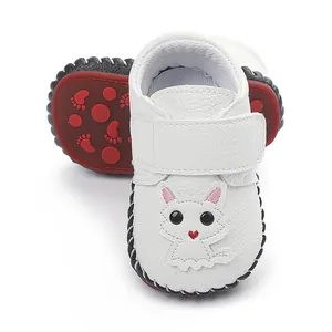Nahaufnahme von weißen Baby-Leder-Schuhen mit Cartoon-Katze und roter rutschfester Sohle