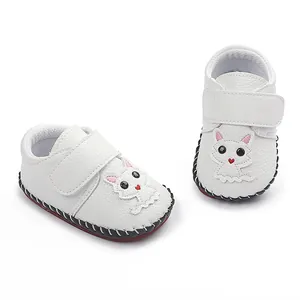 Detailansicht handgenähter weißer Babyschuhe mit Cartoon-Katze und Klettverschluss