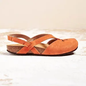 Side view detail of orange suede flat sandals with hollow round toe and cork sole