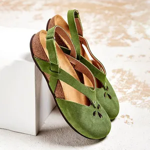 Detailed view of green suede round-toe flat sandals featuring elegant floral cut-out designs.