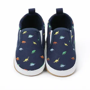 Detailopname van canvas babyschoentjes met kleurrijke dinosauruspatronen en witte zolen