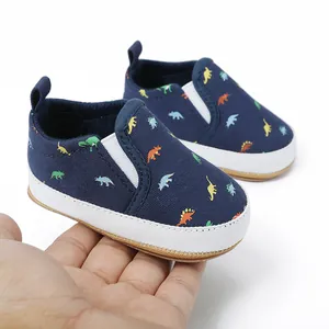 Gedetailleerd zicht op marineblauwe baby canvas instappers met dino-prints