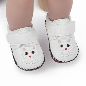 Detailaufnahme weißer Babyschuhe mit süßem Katzenmuster und Handnähten.