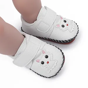 Detailansicht der weißen, handgenähten Babyschuhe mit niedlichem Katzen-Cartoon-Design.