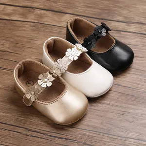 Nahaufnahme von Baby-Prinzessin-Laufschuhen in Gold, Weiß und Schwarz mit Blumendetails.
