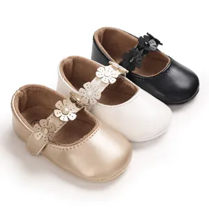 Nahaufnahme von Baby-Lauflernschuhen mit Blumenriemen in Gold, Weiß und Schwarz