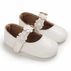 Detailaufnahme weißer Baby-Mary-Janes mit Blumenapplikationen und weichen Laufsohlen