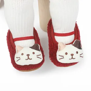 Detailed close-up of cute cat pattern on red fuzzy baby walking shoes for infants.