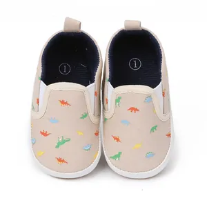 Detail van beige baby instapschoenen met kleurrijke dinosaurus print motief