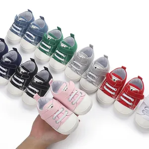Gros plan d'une main tenant des chaussures roses pour bébé avec assortiment de couleurs