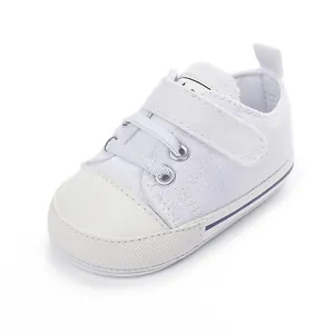 Vue détaillée de la chaussure en toile blanche pour bébé avec bride velcro et embout gomme