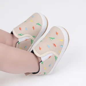 Detailed view of beige baby slip-on shoes featuring colorful dinosaur patterns