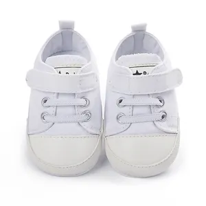 Vue de face détaillée de chaussures de marche bébé en toile blanche avec scratch