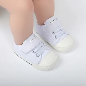 Vue détaillée de baskets en toile blanches pour bébé avec velcro et semelle souple pour petits