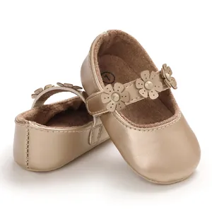 Nahaufnahme von champagnergoldenen Baby-Lernschuhen mit Blumenriemen und weicher Sohle