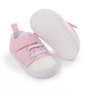 Vue détaillée des chaussures bébé en toile rose montrant la semelle en caoutchouc blanc