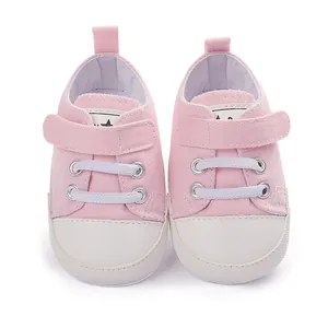 Gros plan de chaussures en toile roses pour bébé avec velcro et embout en caoutchouc