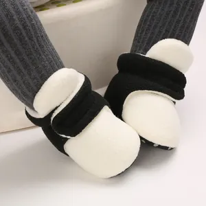 Close-up of soft black and white plush baby booties with grey ribbed leggings