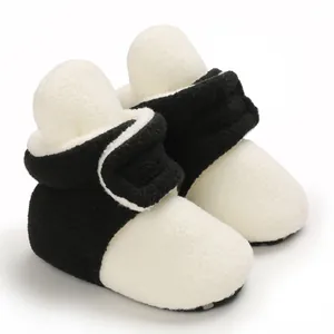 Close-up of black and white plush baby winter booties with soft sole and velcro strap