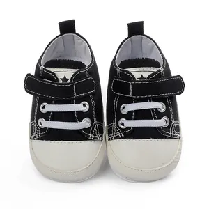 Vue de face de chaussures en toile noire pour bébé avec fermeture velcro et bout
