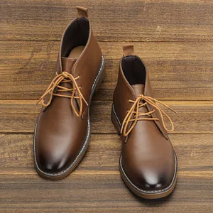 Vista dall'alto dei classici stivaletti desert boot da uomo in pelle marrone su legno
