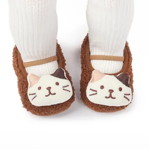Detail view of cute brown plush baby walking shoes with cartoon cat face design.