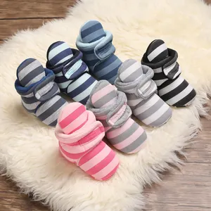 Detailansicht bunter gestreifter Fleece-Baby-Winterstiefel auf einem weißen Teppich