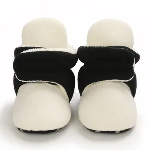 Close-up detail of soft black and white sherpa fleece baby booties for winter infants
