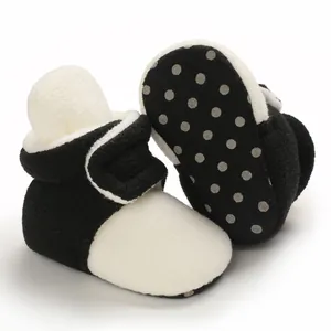 Detail of soft-soled black and white baby booties with non-slip dotted bottom.