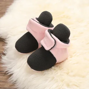 Close-up of pink and black baby winter plush shoes with velcro strap on soft rug.