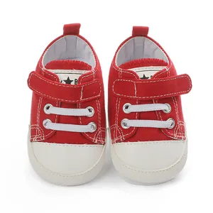 Vue détaillée de chaussures en toile rouge pour bébé avec lacets blancs et velcro.