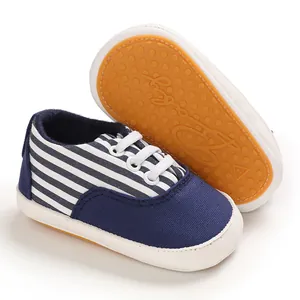Détail d'une chaussure bébé avec rayures bleues et semelle en caoutchouc antidérapante.