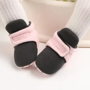 Close-up of soft pink and black fleece baby booties designed for autumn and winter