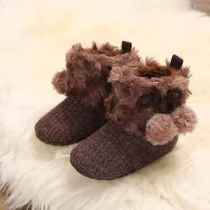 Detail view of cute brown baby knit boots featuring soft faux fur trim and pom-pom decor