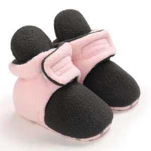 Close-up of soft fleece baby booties in pink and black with hook and loop closure