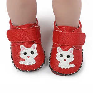 Detail von roten Babyschuhen mit niedlichem weißen Katzen-Patch und Klettverschluss.