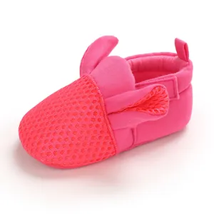 Dettaglio ravvicinato di scarpine neonato in mesh rosa con orecchie di coniglio e suola morbida.