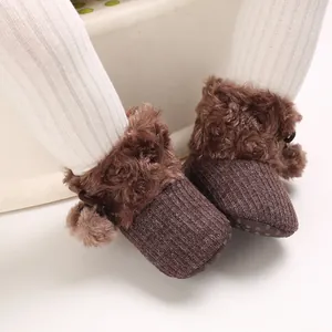 Close-up of cute brown baby princess shoes with fuzzy fur and pom-pom details