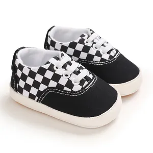 Vue détaillée de chaussures de marche pour bébé au motif en damier noir et blanc classique.