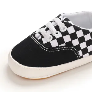 Gros plan de chaussures pour bébé en toile à carreaux noir et blanc avec semelles souples