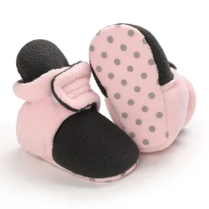 Detailed view of pink and black baby fleece booties with soft non-slip dotted soles