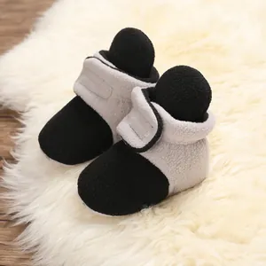Close-up of soft-soled color-block baby winter booties on a white plush rug