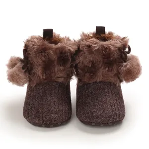 Detail of brown infant winter boots with faux fur trim and cute pom-poms