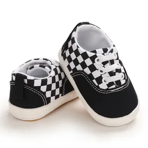 Gros plan de chaussures de marche pour bébé à damier noir et blanc, semelle souple.