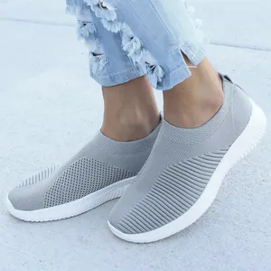 Detail van grijze ademende mesh slip-on sneakers voor dames op betonnen grond.